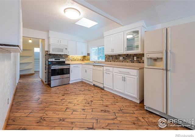 kitchen with lofted ceiling with skylight, light wood-style floors, white appliances, backsplash, and white cabinetry