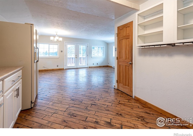 interior space featuring an inviting chandelier, a textured ceiling, and baseboards