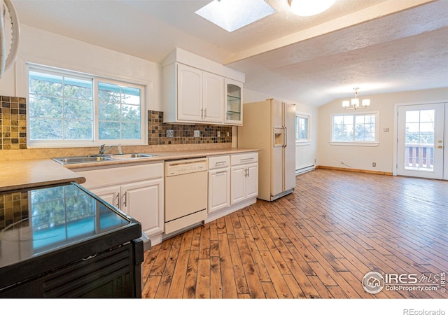 kitchen featuring a sink, lofted ceiling with skylight, a chandelier, light wood-style floors, and white appliances