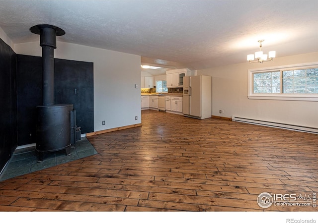 unfurnished living room with a textured ceiling, a wood stove, and dark wood finished floors