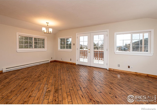 empty room with a baseboard heating unit, lofted ceiling, hardwood / wood-style floors, and an inviting chandelier