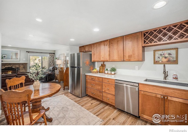kitchen with light countertops, light wood-type flooring, appliances with stainless steel finishes, and a sink