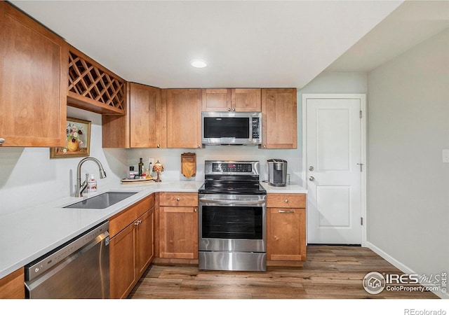 kitchen featuring recessed lighting, stainless steel appliances, light countertops, wood finished floors, and a sink
