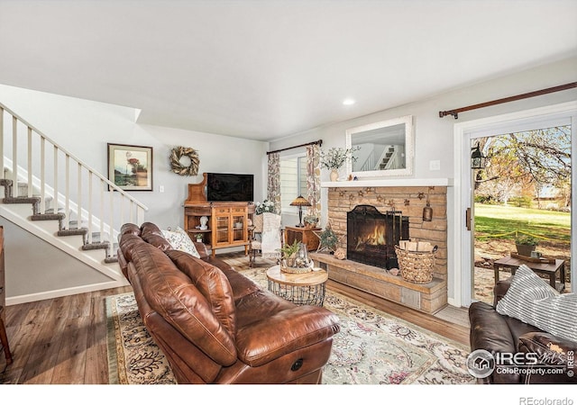 living room featuring wood finished floors, a fireplace, stairway, and a healthy amount of sunlight