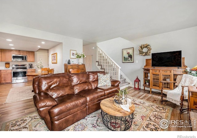 living area with light wood-type flooring, baseboards, recessed lighting, and stairs