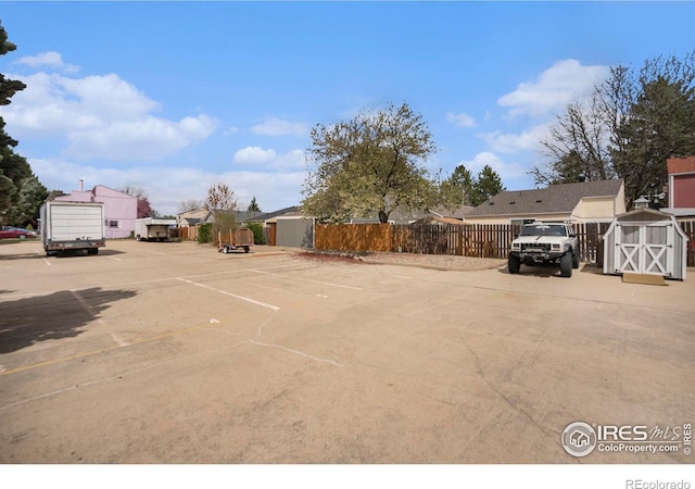 uncovered parking lot with fence and a storage unit