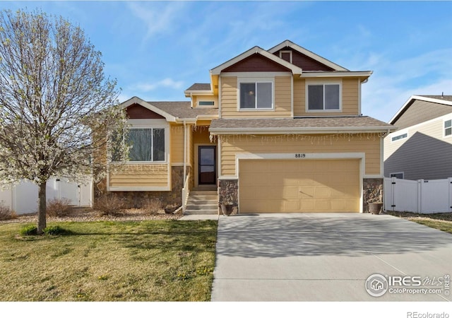craftsman house with fence, driveway, stone siding, a front yard, and a garage