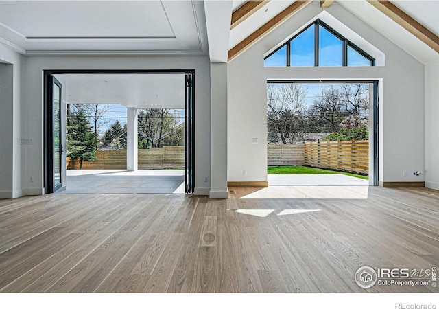 entryway with lofted ceiling with beams, baseboards, a healthy amount of sunlight, and wood finished floors