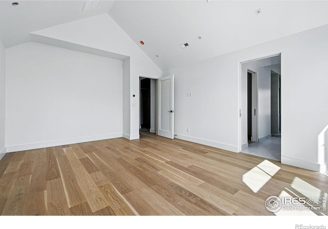 interior space with light wood finished floors, visible vents, and lofted ceiling