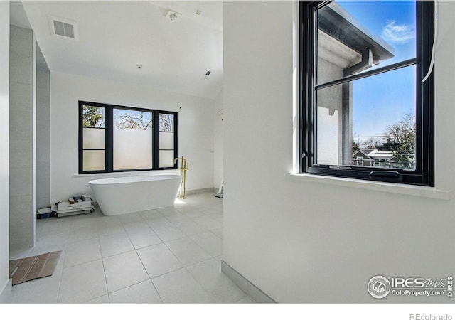 bathroom featuring baseboards, tile patterned flooring, a soaking tub, and visible vents