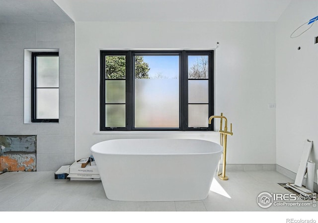 bathroom with a soaking tub, baseboards, and tile patterned floors