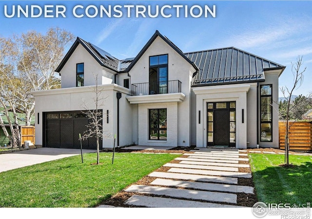 modern farmhouse featuring fence, a balcony, concrete driveway, stucco siding, and a standing seam roof