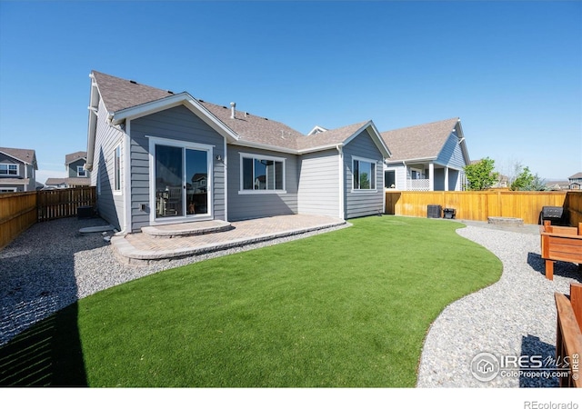 rear view of property with a yard, roof with shingles, a fenced backyard, and a patio area