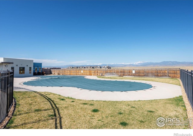 view of pool with a yard, a fenced in pool, a mountain view, and a fenced backyard