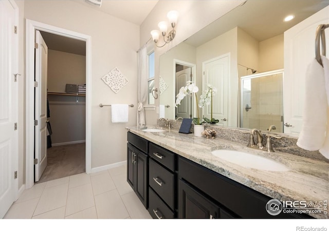 bathroom featuring double vanity, a spacious closet, a sink, and a stall shower