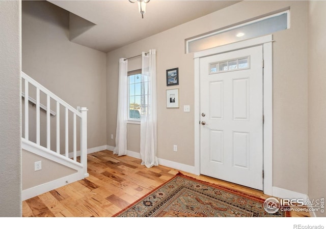 entrance foyer featuring baseboards, wood finished floors, and stairs