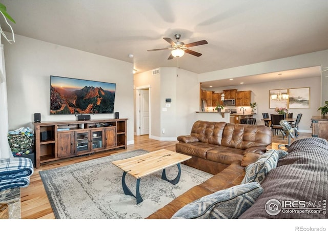 living area with light wood-style floors, visible vents, baseboards, and ceiling fan with notable chandelier