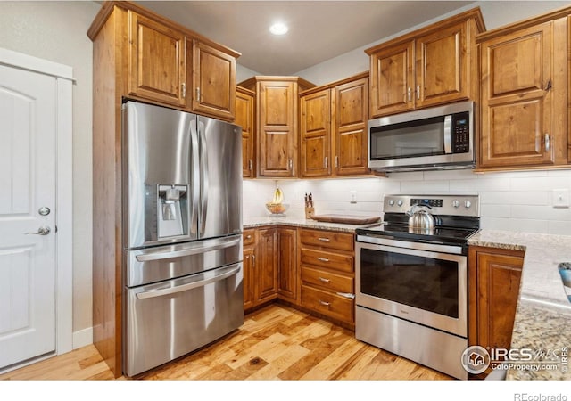 kitchen featuring stainless steel appliances, brown cabinetry, and light wood-style floors