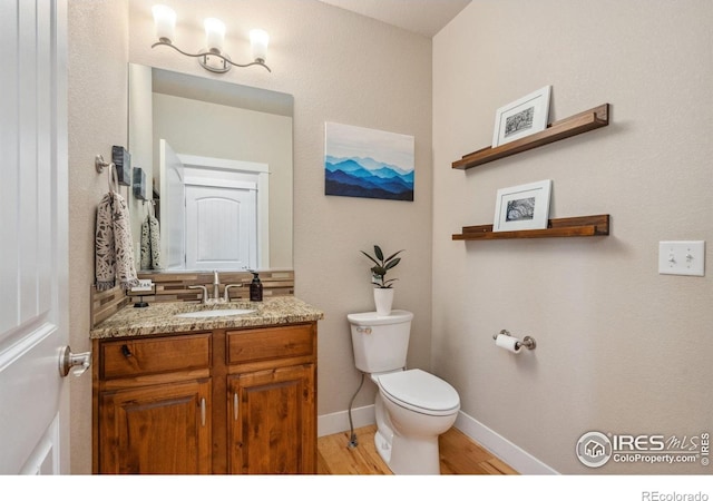 bathroom with baseboards, wood finished floors, vanity, and toilet