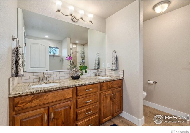 bathroom featuring tasteful backsplash, toilet, wood finished floors, and a sink
