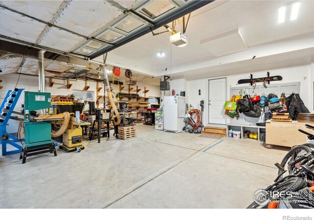 garage featuring freestanding refrigerator, a workshop area, and a garage door opener