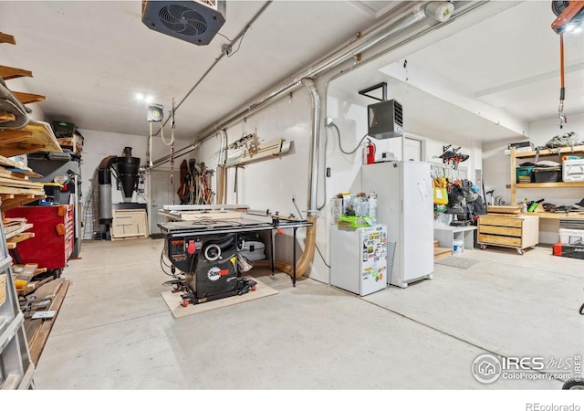 garage with freestanding refrigerator, a workshop area, and a garage door opener