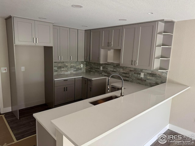 1687 Valency Dr, Loveland, CO 80537 - kitchen featuring a sink, open shelves, gray cabinetry, backsplash, and a textured ceiling