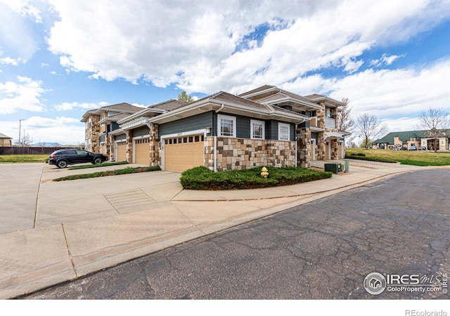 view of front of property featuring a garage, stone siding, and concrete driveway