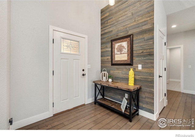 entrance foyer featuring baseboards, wood finished floors, and wooden walls