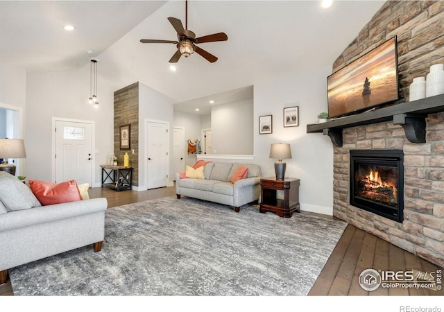 living area featuring baseboards, high vaulted ceiling, a ceiling fan, hardwood / wood-style floors, and a fireplace