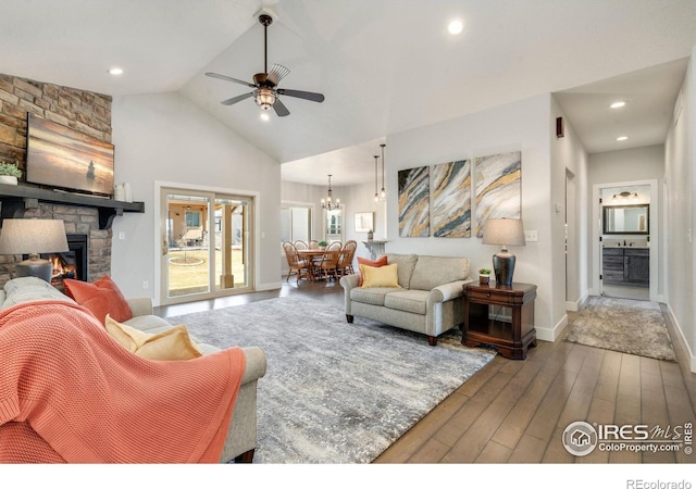 living room featuring baseboards, recessed lighting, ceiling fan with notable chandelier, hardwood / wood-style flooring, and a fireplace