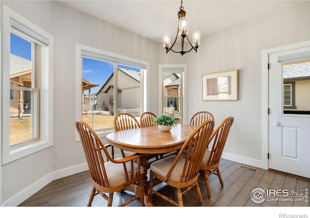 dining space featuring baseboards, visible vents, an inviting chandelier, and dark wood-style flooring