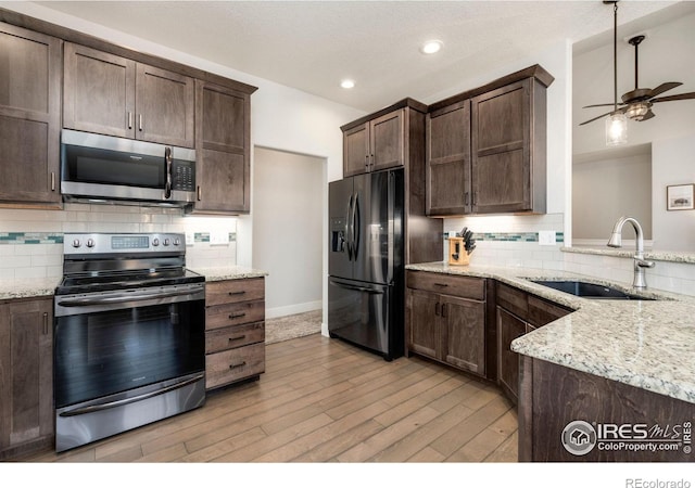 kitchen with a sink, light wood-style floors, ceiling fan, dark brown cabinetry, and appliances with stainless steel finishes