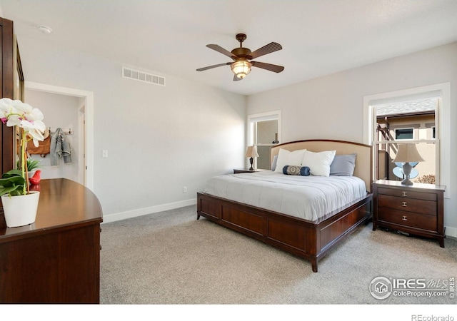 bedroom featuring visible vents, a ceiling fan, baseboards, and light carpet