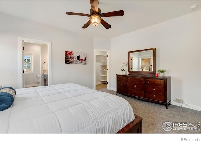 carpeted bedroom with a ceiling fan, baseboards, a spacious closet, and connected bathroom