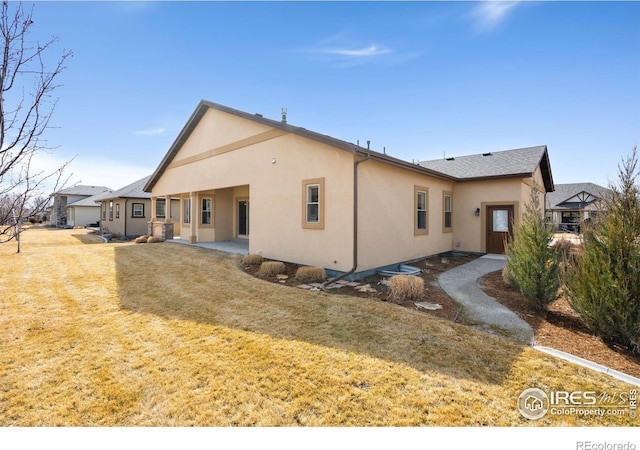 back of property with a yard and stucco siding