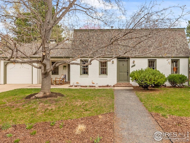 view of front of house with brick siding, driveway, a shingled roof, and a front lawn