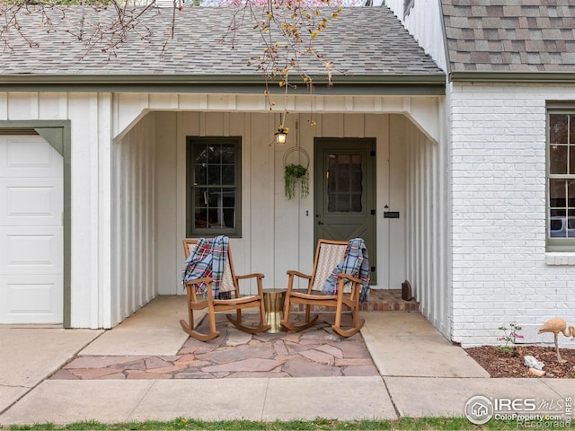 doorway to property featuring brick siding, roof with shingles, and board and batten siding