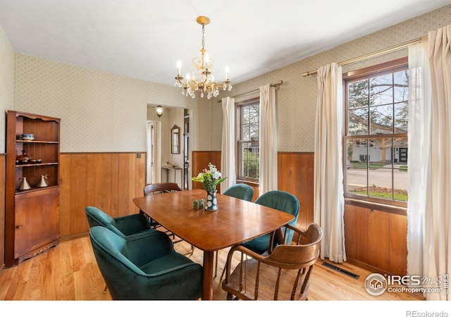 dining space featuring wainscoting, a notable chandelier, visible vents, and a healthy amount of sunlight