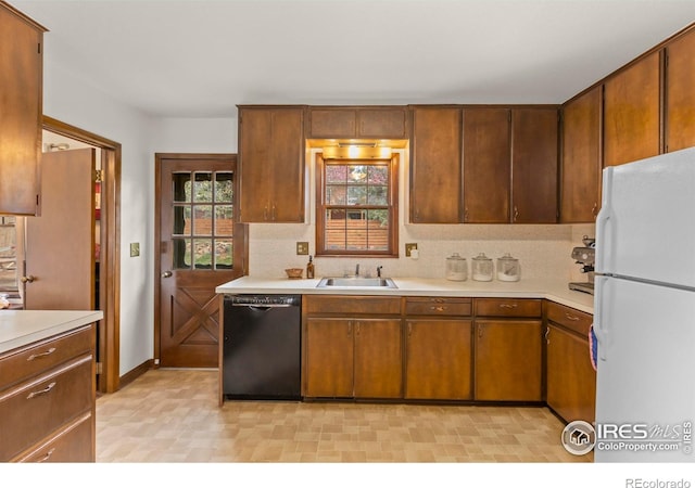kitchen with dishwasher, a sink, light countertops, and freestanding refrigerator