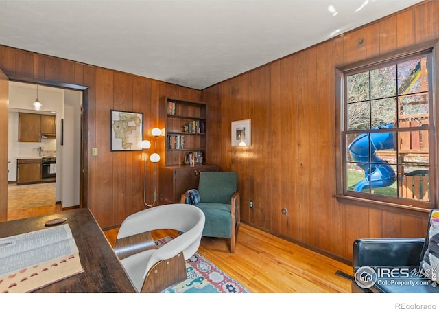 living area with wood finished floors, wood walls, and baseboards