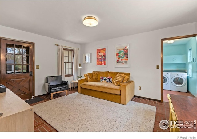 living room featuring washing machine and dryer, brick floor, and baseboards