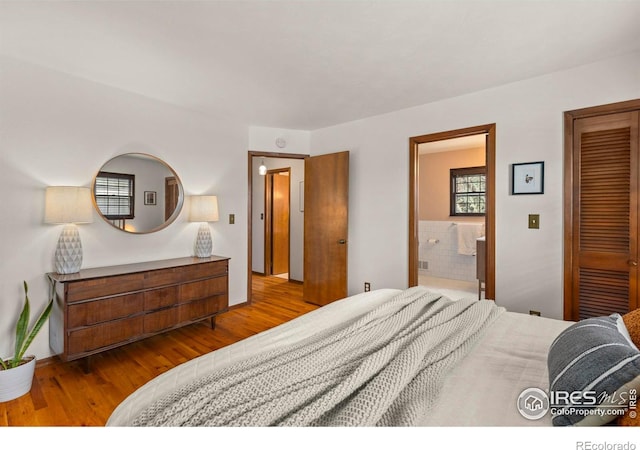 bedroom featuring baseboards, ensuite bath, and wood finished floors