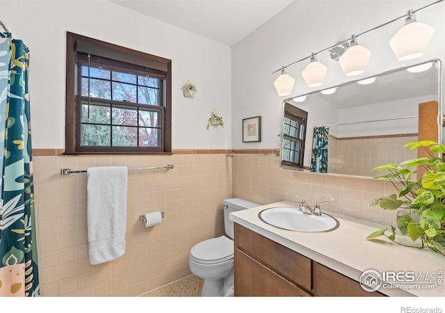 full bath with toilet, tile walls, wainscoting, speckled floor, and vanity