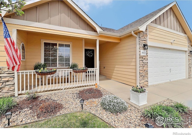 view of front of home with a porch, stone siding, board and batten siding, and a garage