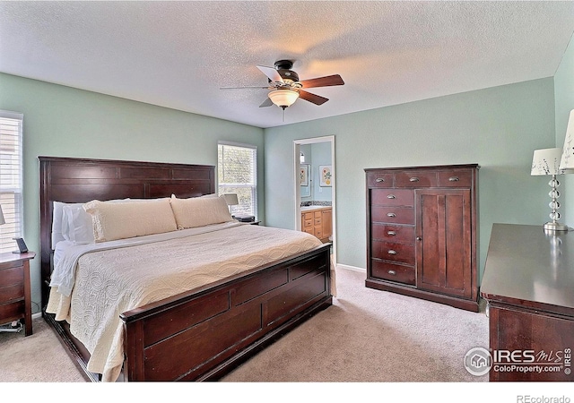carpeted bedroom with ceiling fan, ensuite bath, a textured ceiling, and baseboards