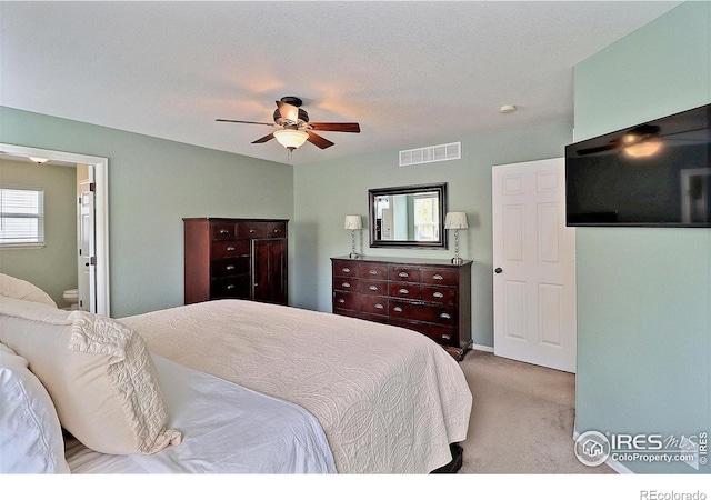 carpeted bedroom featuring ceiling fan, ensuite bathroom, and visible vents