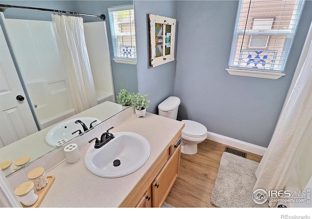 bathroom featuring toilet, wood finished floors, vanity, baseboards, and visible vents