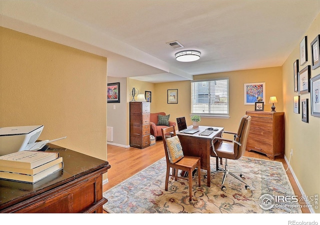 office space with baseboards, light wood-style flooring, and visible vents