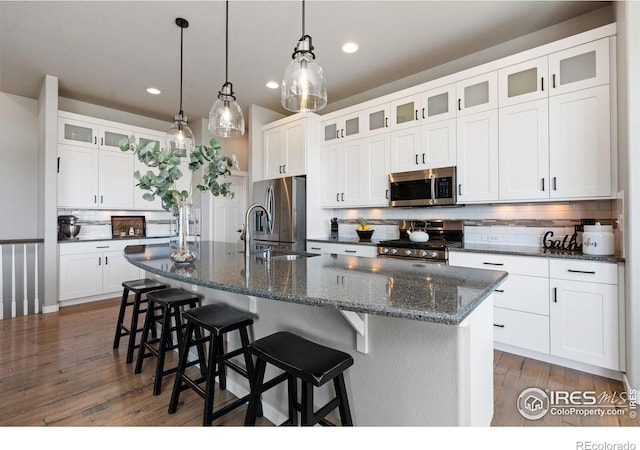 kitchen featuring recessed lighting, stainless steel appliances, wood finished floors, a sink, and decorative backsplash
